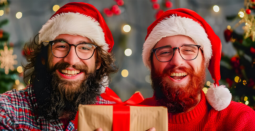 Two bearded brothers in Santa hats exchanging a Christmas gift, festive holiday celebration