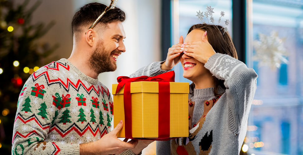 Girl with eyes covered receiving a Christmas gift from her boyfriend, surprise holiday present moment