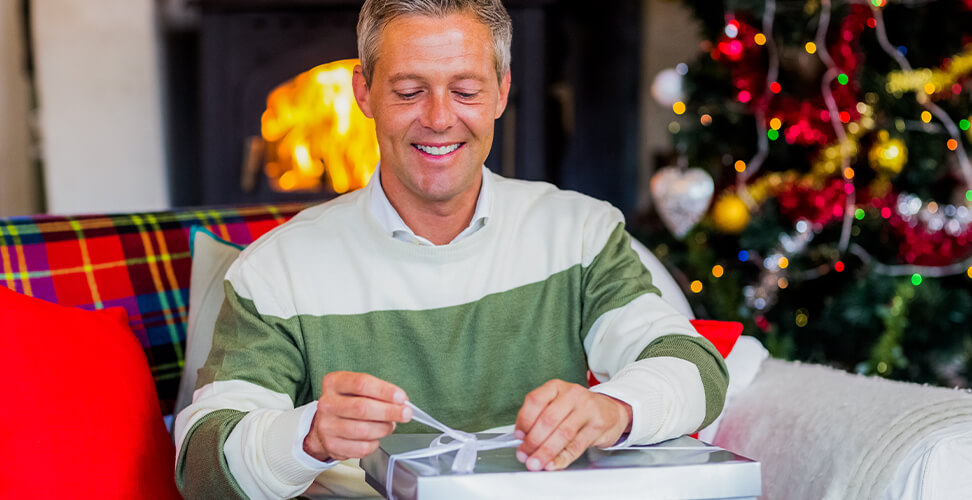 Man opening Christmas present &ndash; festive gift unboxing, holiday surprise moment, seasonal gift experience for him