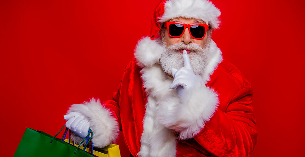 Santa Claus in sunglasses holding shopping bags, finger on lips, perfect for Secret Santa and festive fun