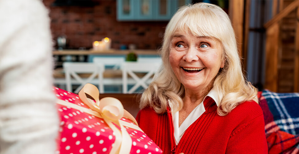 Grandma receiving a gift with a happy smile, heartfelt moment and personalised present idea for grandparents