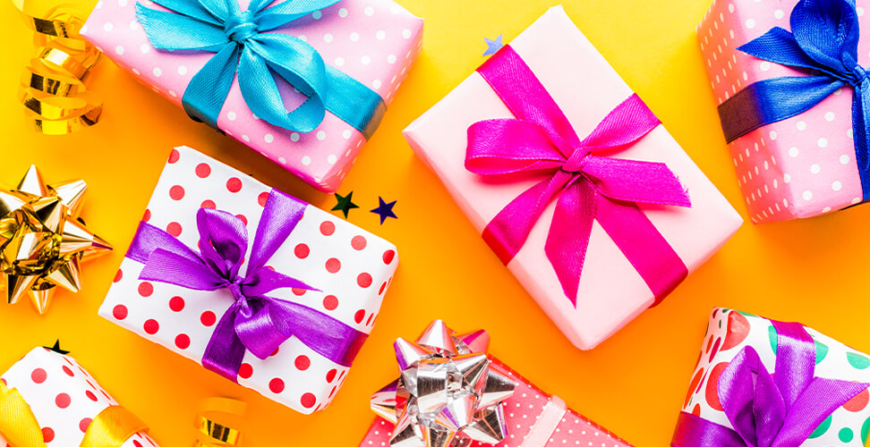 Scattered wrapped presents in bright vibrant colours – festive gift ideas for birthdays, Christmas, and celebrations