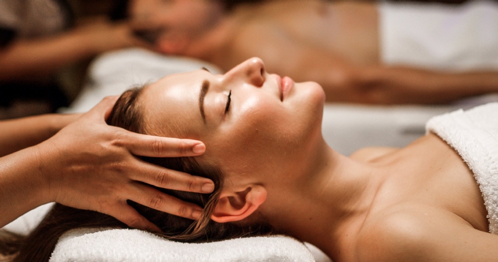 Close-up of a woman with closed eyes enjoying a relaxing head massage at a spa.