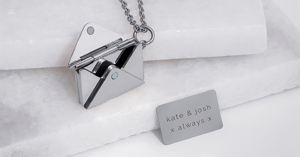 An open silver envelope necklace revealing a personalized message card inside, on a white background.