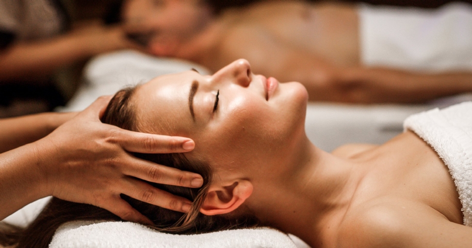 Close-up of a woman enjoying a head massage with her eyes closed in a serene spa setting.
