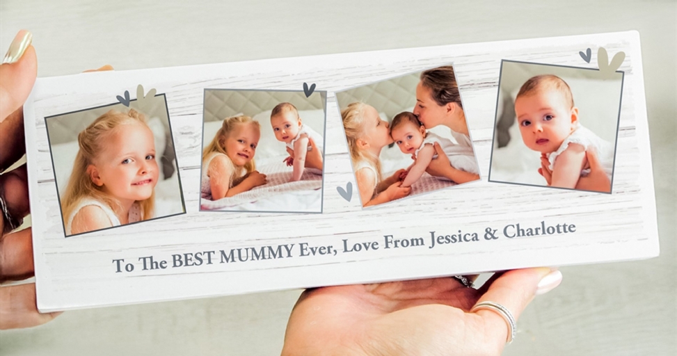 A personalized photo plaque for 'The BEST MUMMY Ever' held by hands, featuring photos of two young girls and a baby.
