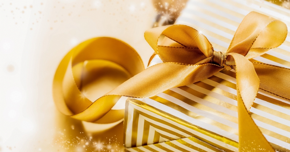 Elegant gold and white striped gift box with a large golden ribbon and festive sparkles.