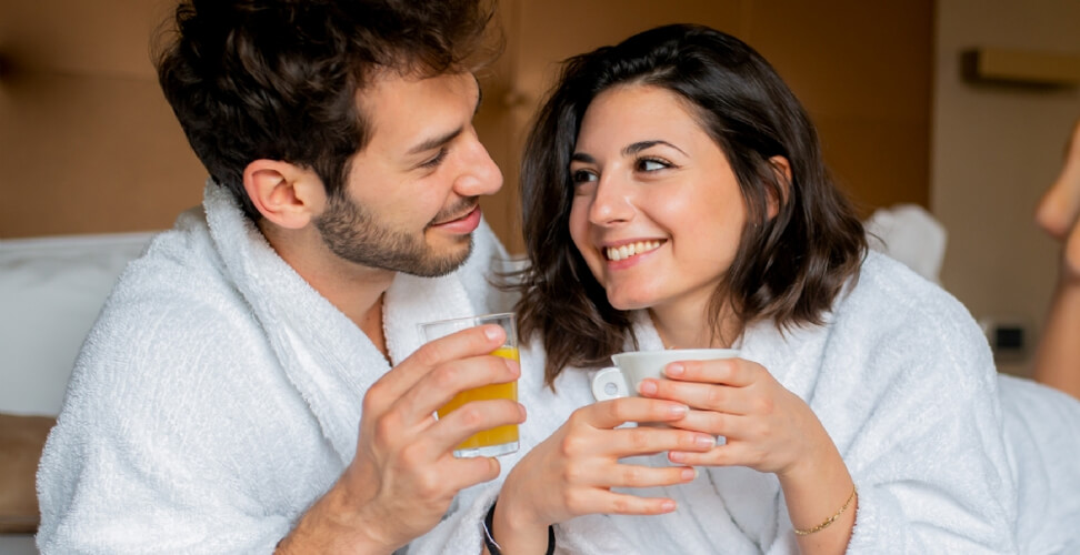 Couple in hotel robes enjoying breakfast in bed – romantic getaway experience, luxury stay, and relaxing couple’s retreat