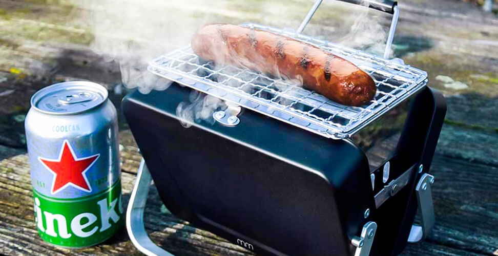 World's smallest BBQ cooking a sausage with a beer beside it &ndash; quirky miniature grill gift idea
