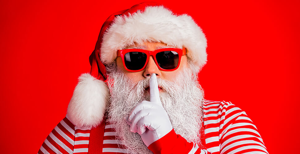Cheeky Santa in sunglasses with finger over lips