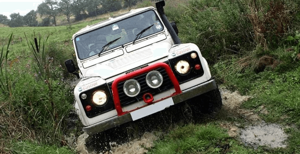 A white car driving through a muddy area