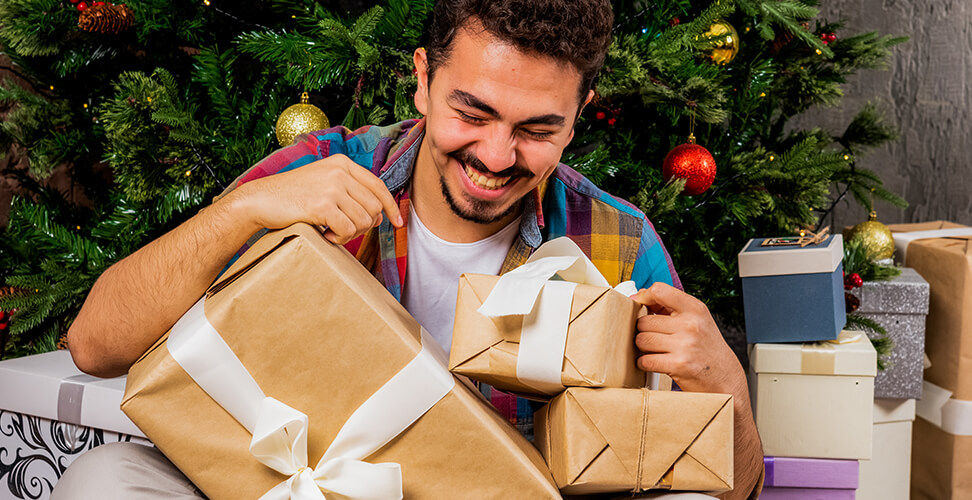 Man laughing while surrounded by Christmas gifts during White Elephant gift exchange