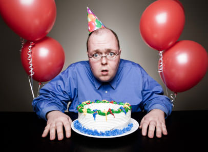 Surprised man with his birthday cake and balloons