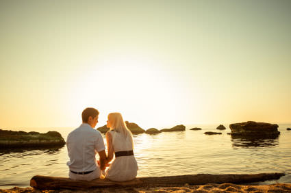 Couple sitting by the water watching the sunset