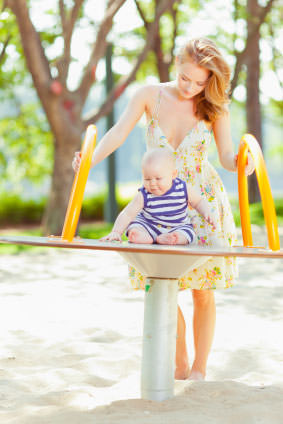 Mother playing with baby boy on seesaw